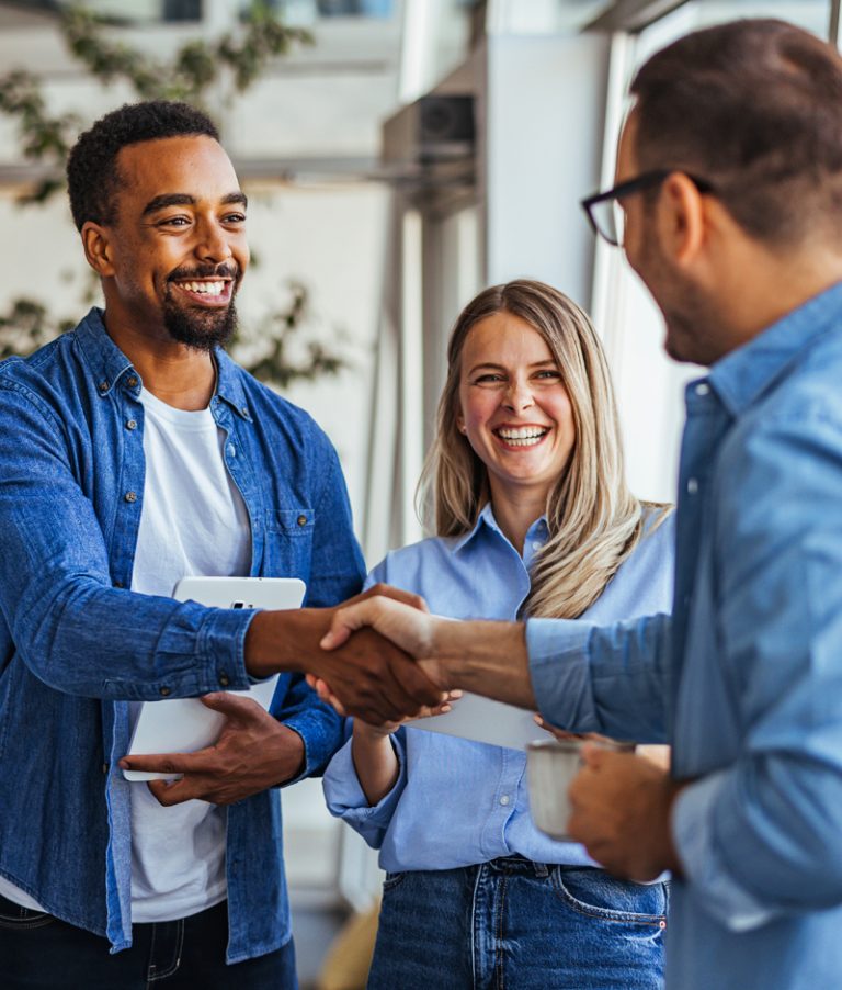 A Black executive pastor shaking hands with a church volunteer, while a church staff looks on smiling